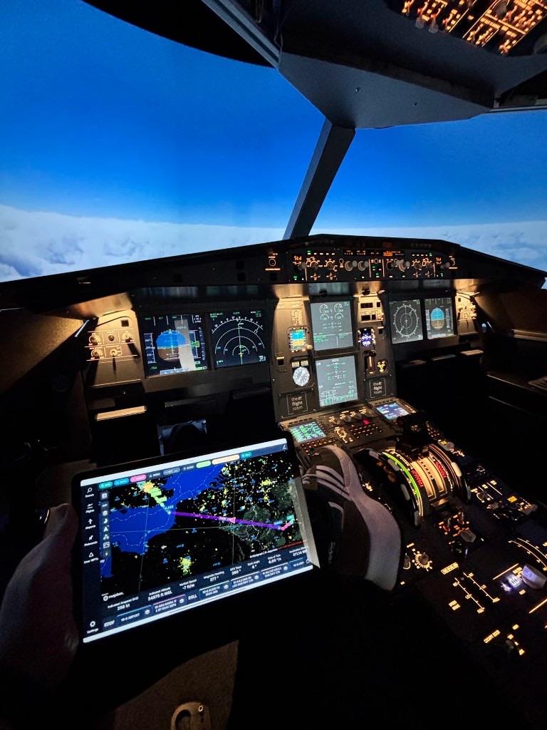 Pogled iz A320 kokpita u krstarenju iznad oblaka, s tabletom koji prikazuje rutu leta